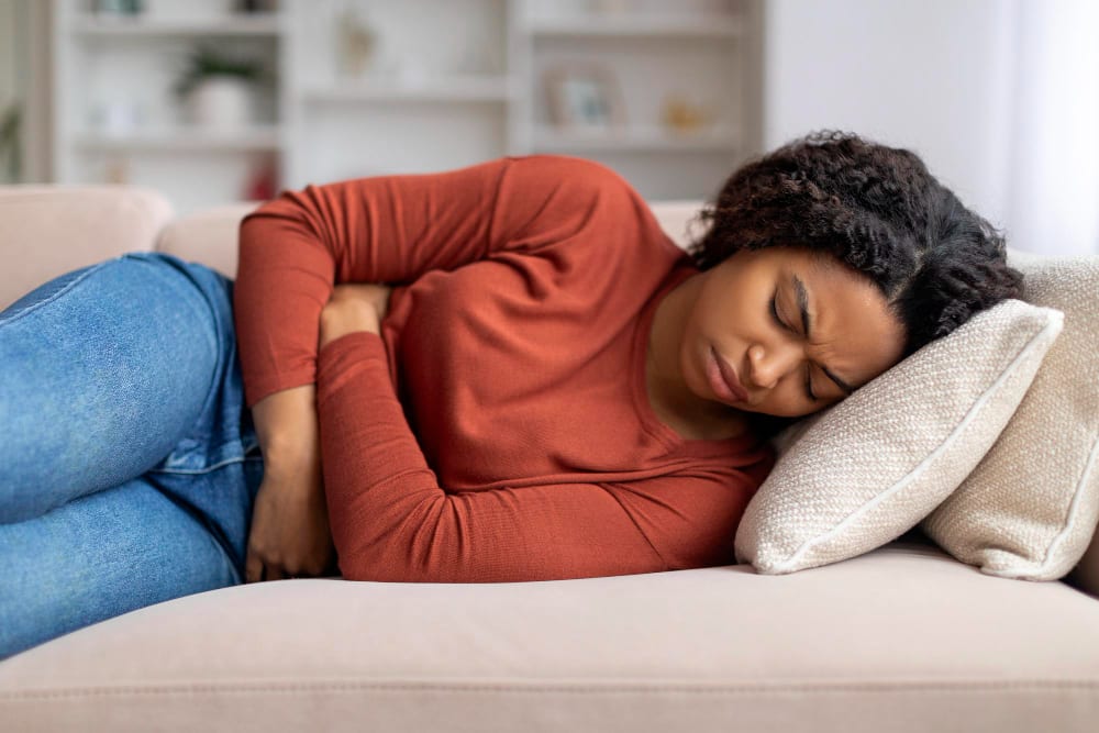 Woman lying on a couch holding her abdomen in pain