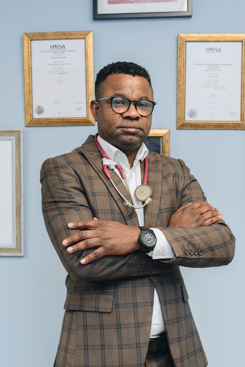 Dr Malonda Makanda standing with arms folded in his consulting room, stethoscope around his neck